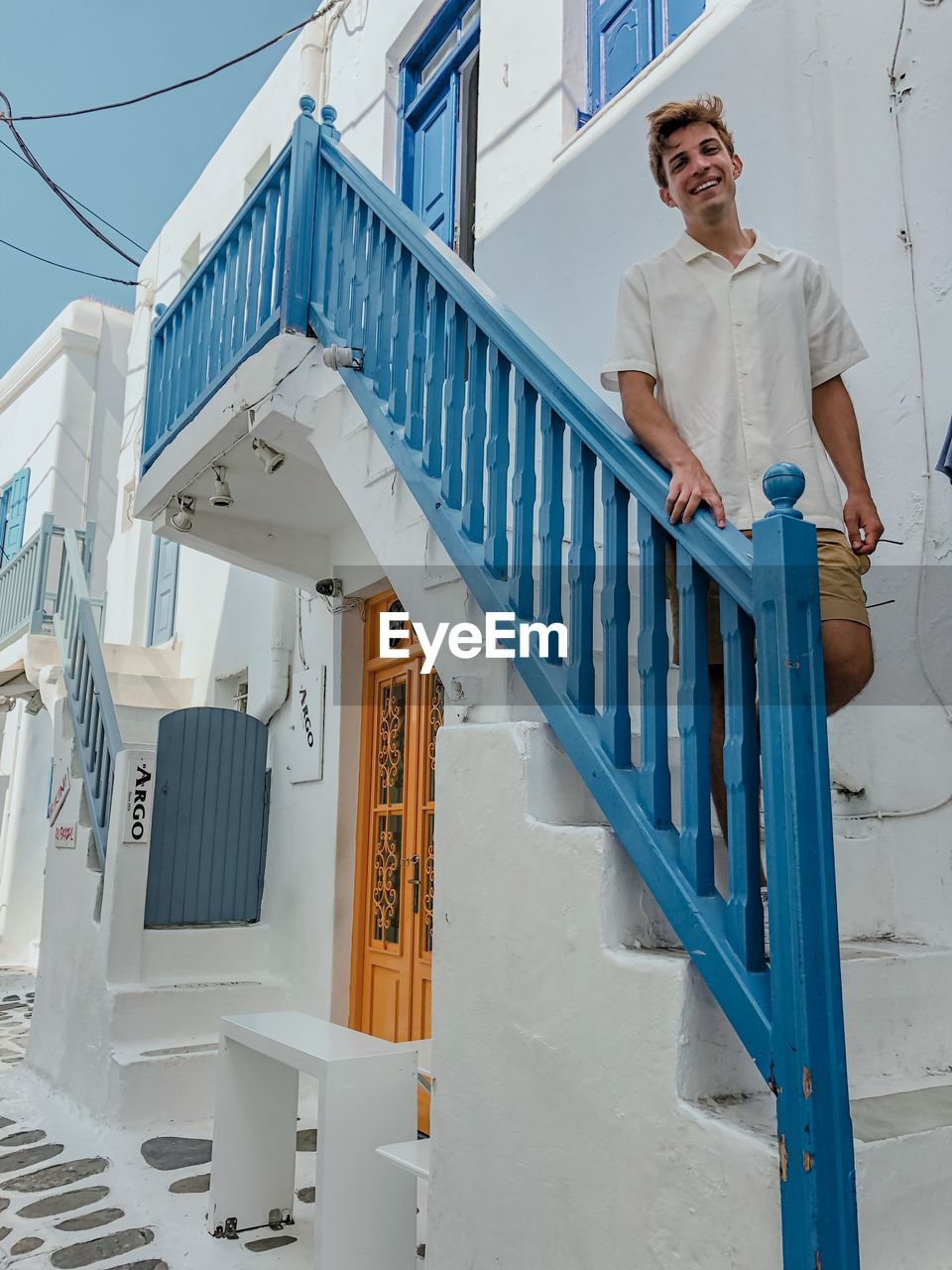 FULL LENGTH PORTRAIT OF YOUNG MAN STANDING ON STAIRCASE AGAINST BUILDING