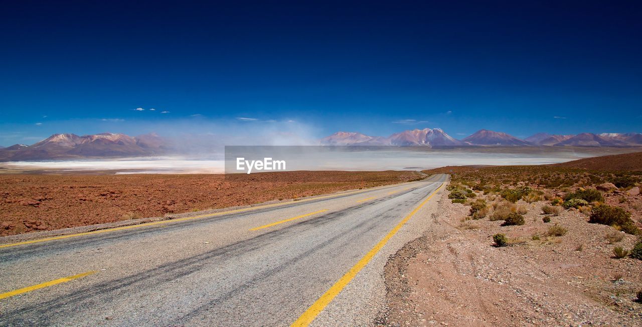 Road by desert against sky