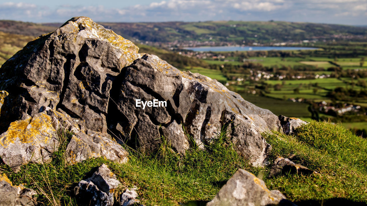 Close-up of rock on landscape against sky