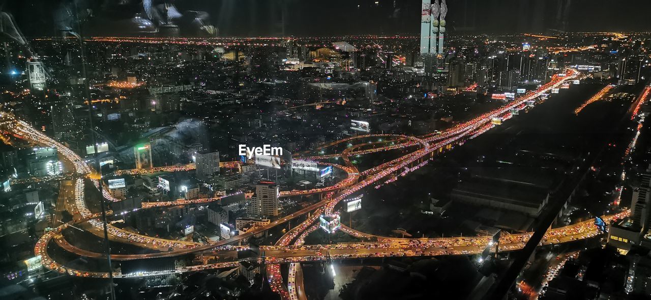 HIGH ANGLE VIEW OF ILLUMINATED CITY STREET AND BUILDINGS AT NIGHT