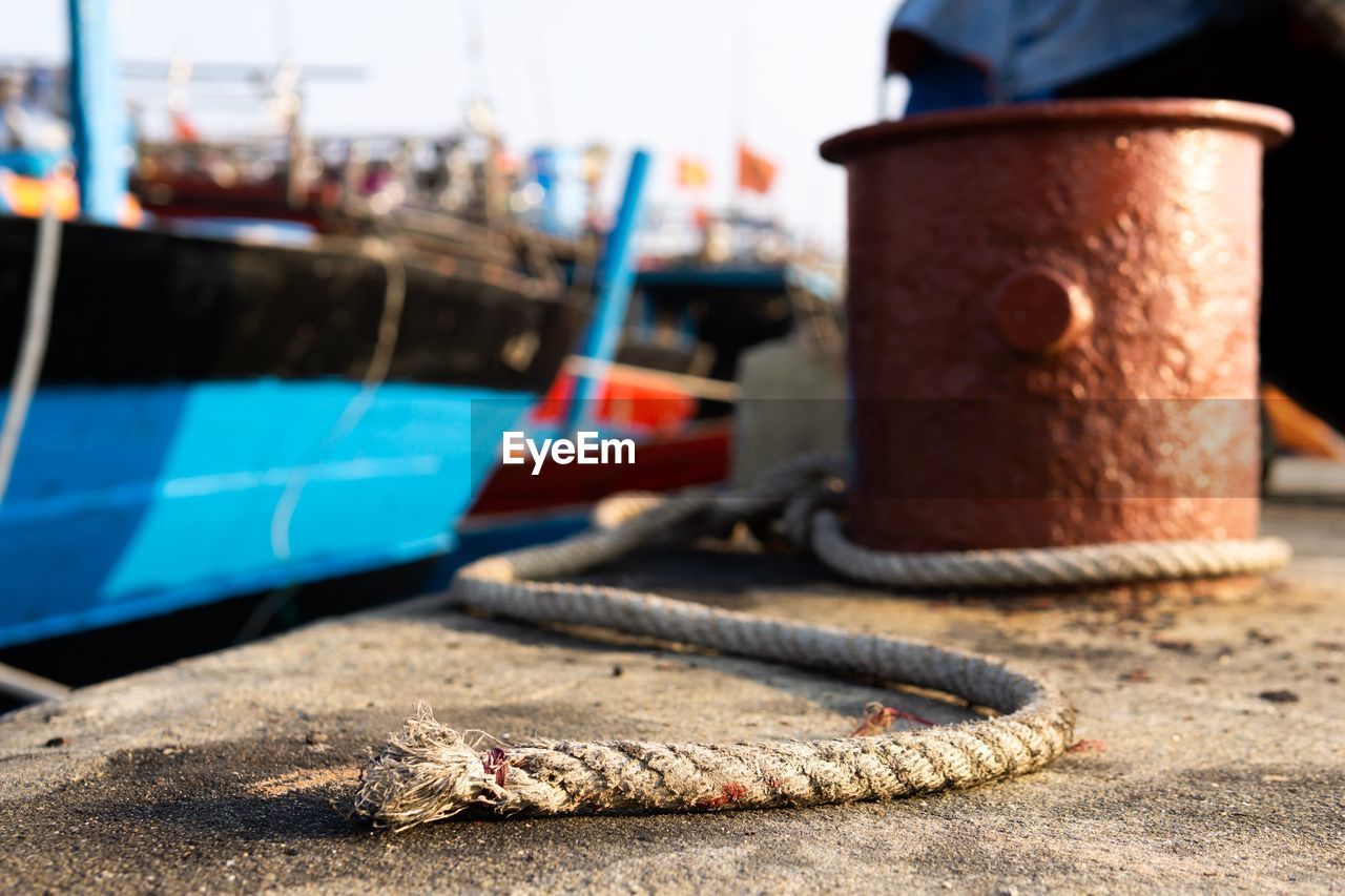 CLOSE-UP OF ROPE TIED TO BOLLARD