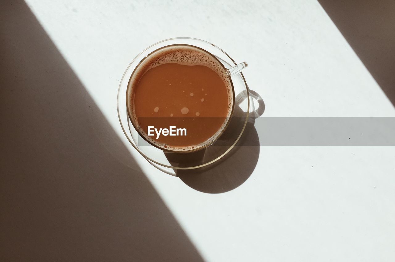 HIGH ANGLE VIEW OF COFFEE CUP ON TABLE AGAINST WALL