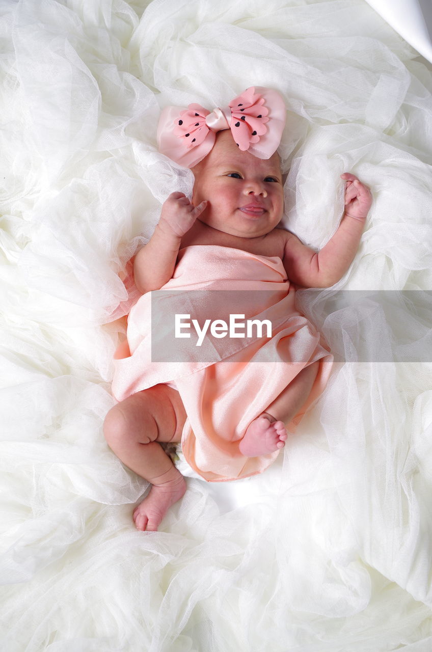 High angle view of cute baby girl lying on bed at home