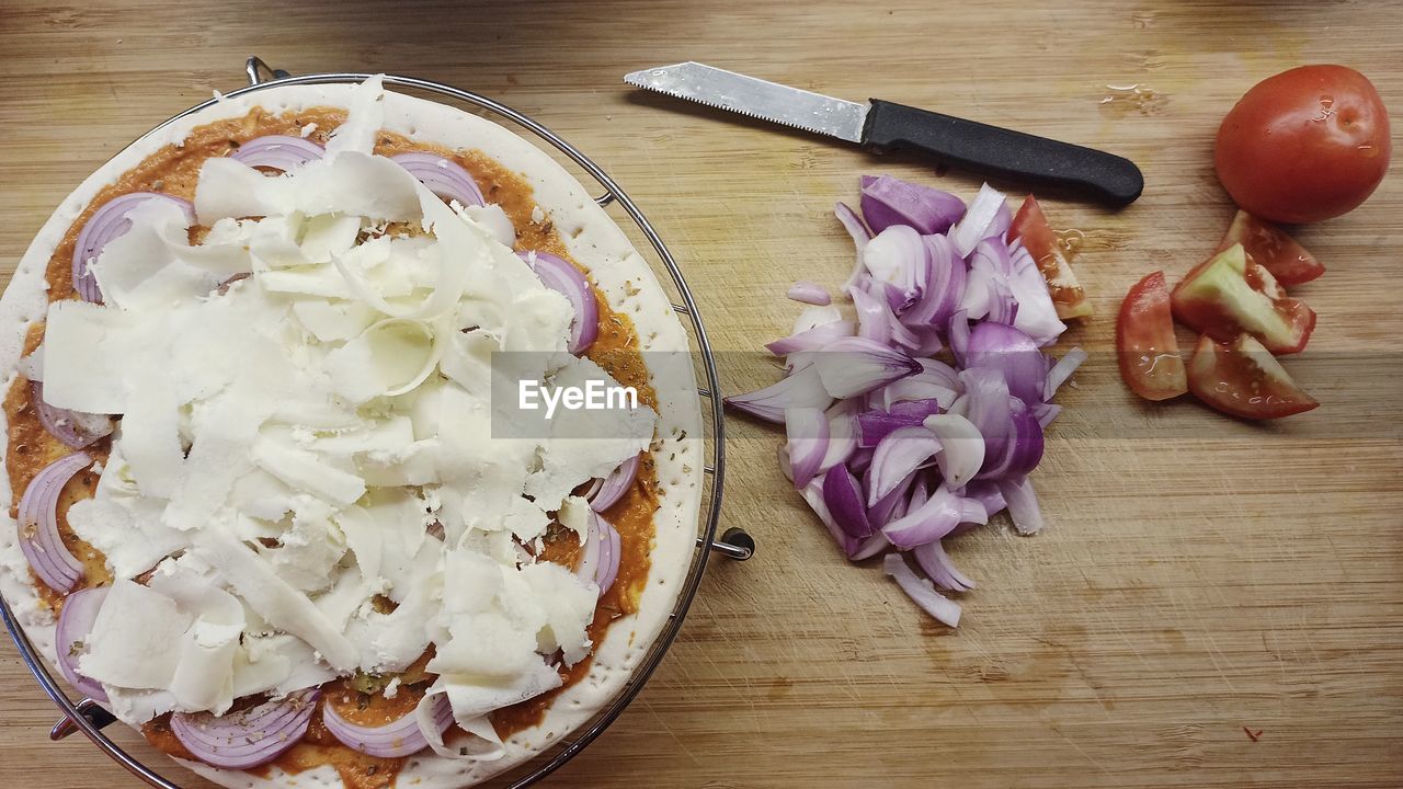 food, food and drink, freshness, kitchen knife, dish, table, wood, vegetable, indoors, produce, high angle view, healthy eating, knife, onion, no people, fast food, red onion, directly above, wellbeing, still life, cutting board, plant, flower, eating utensil, dairy, kitchen utensil, weapon, plate, dessert, fruit, cheese