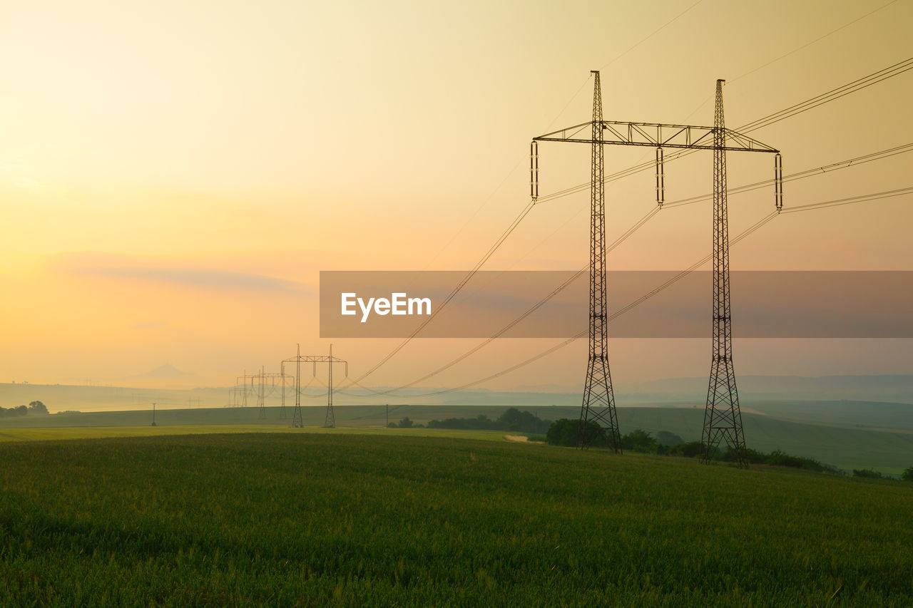 ELECTRICITY PYLON ON FIELD DURING SUNSET