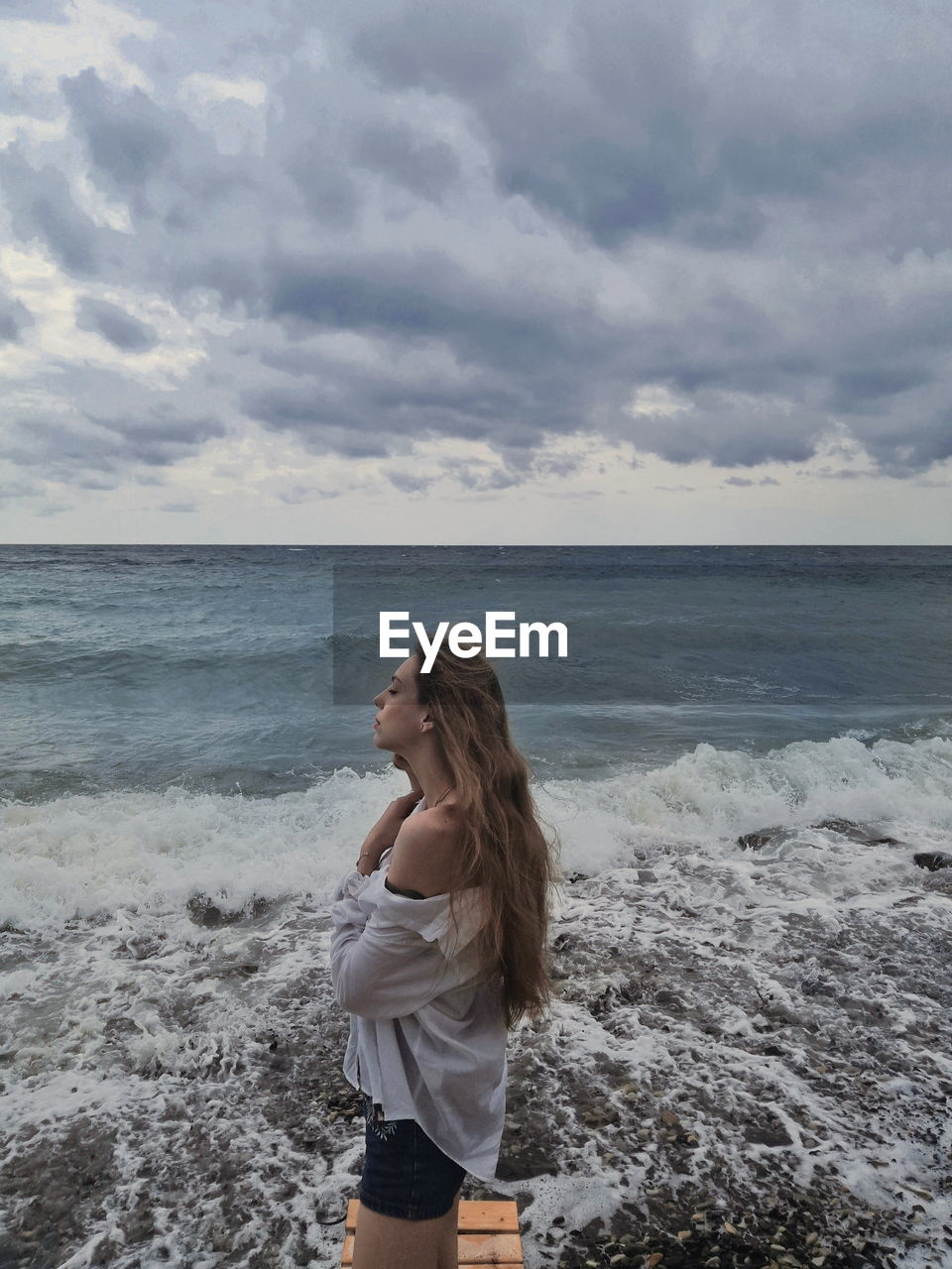 Woman standing at beach against side view
sky