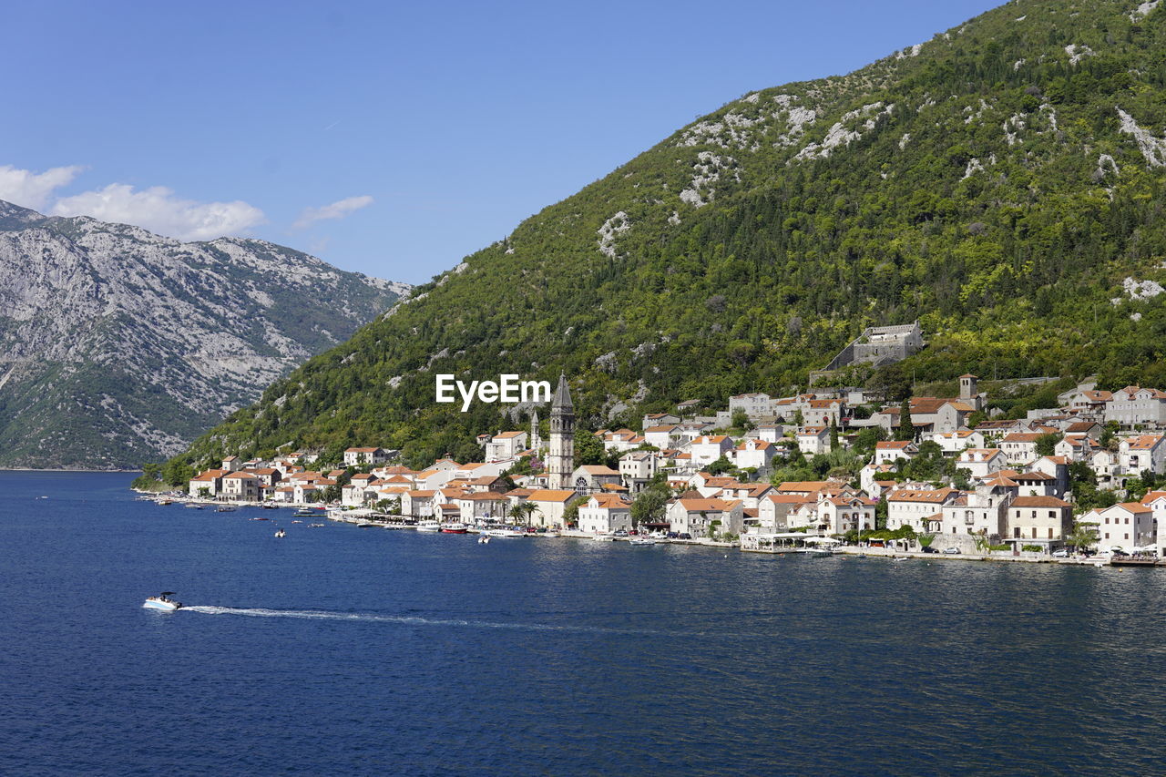 Scenic view of town by sea against sky