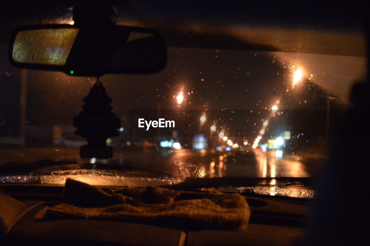 Close-up of illuminated street lights seen from car windshield at night