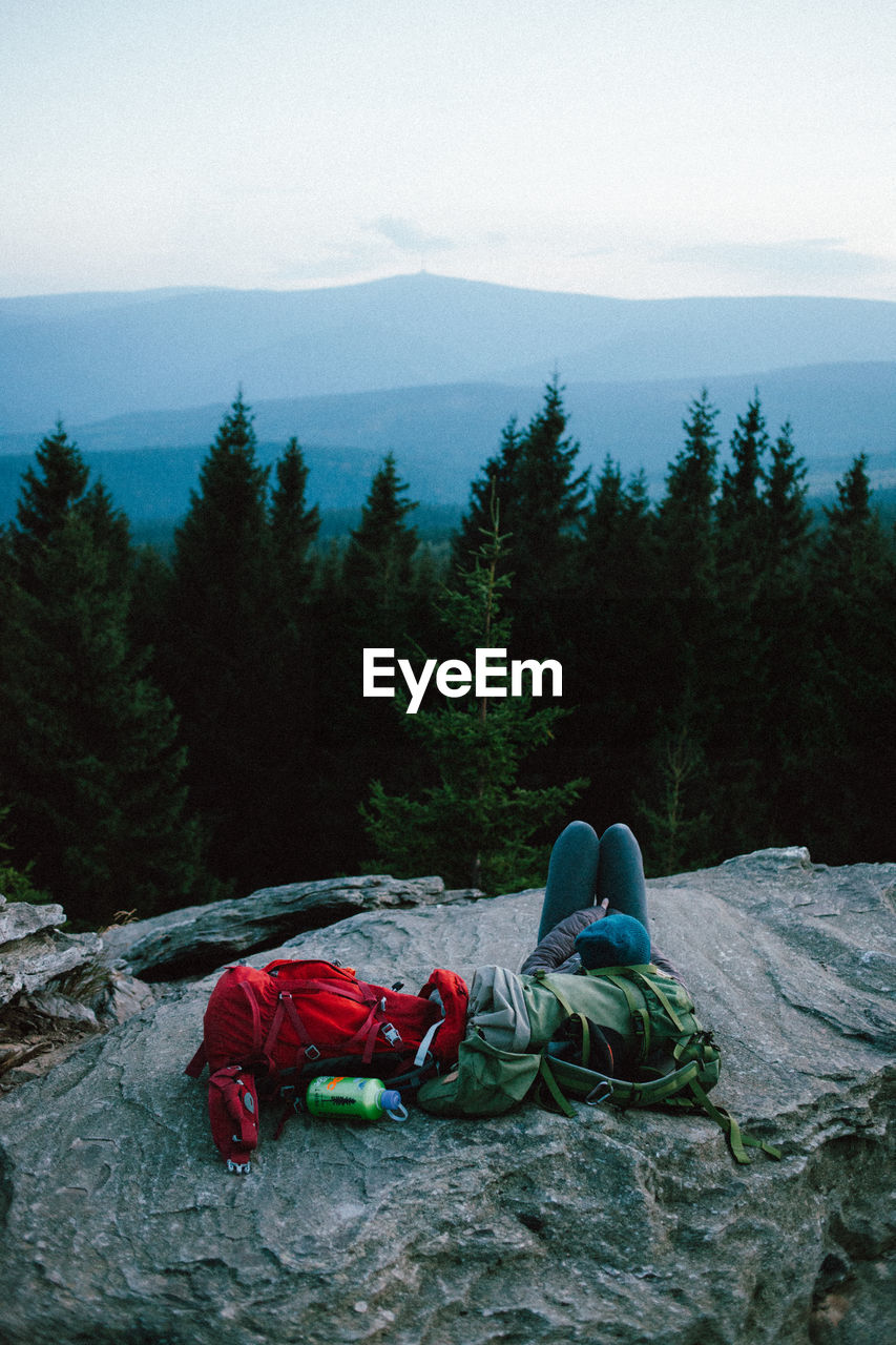 High angle view of person resting on mountain against sky in forest