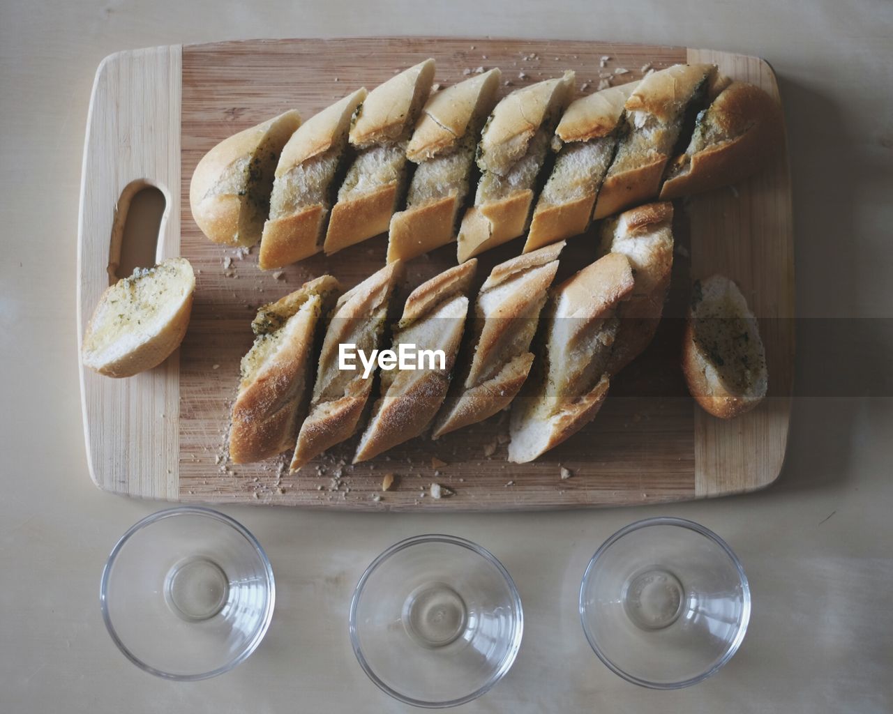 Directly above shot of bread slices on chopping board by glasses