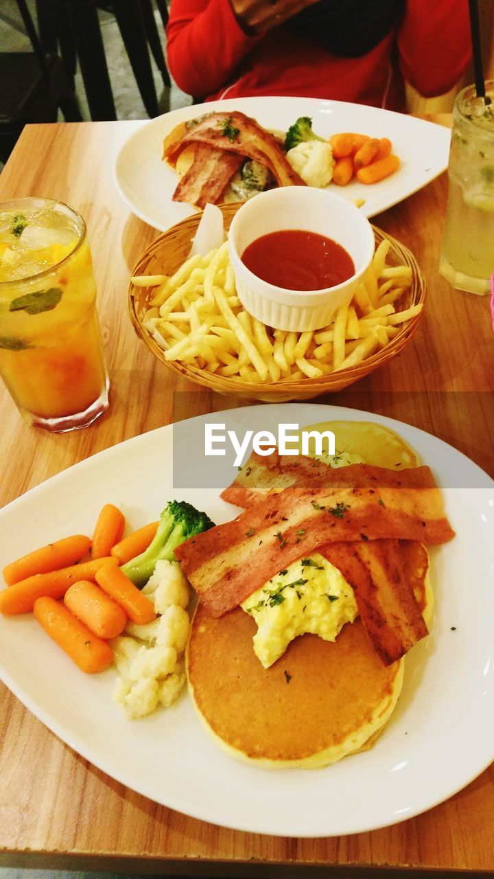 High angle view of pancakes served with french fries and bacon on table
