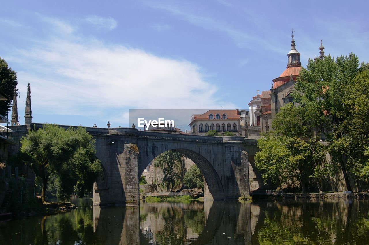 Bridge over river by cathedral against sky