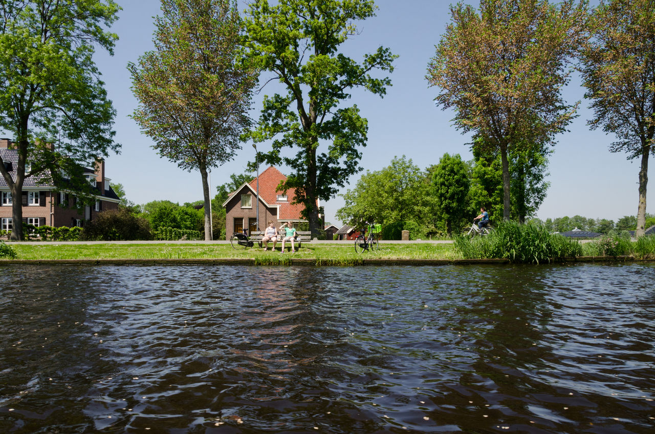 SCENIC VIEW OF LAKE BY TREES AND BUILDING