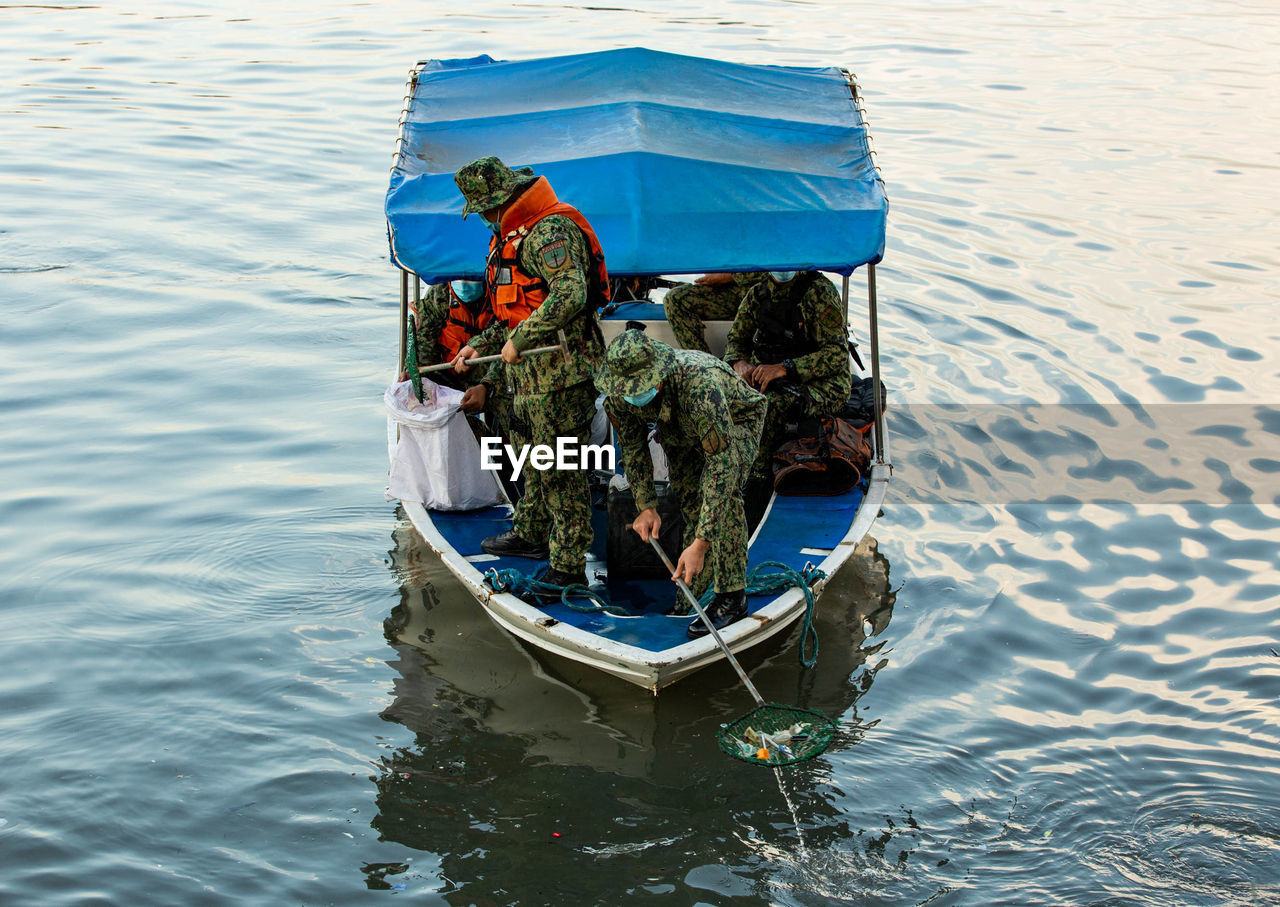 HIGH ANGLE VIEW OF MEN ON BOAT IN SEA
