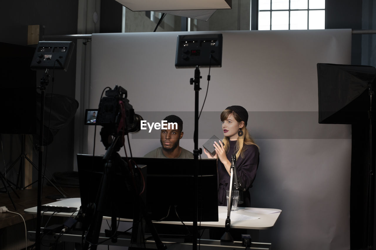 Female entrepreneur explaining about product with male colleague while recording on camera