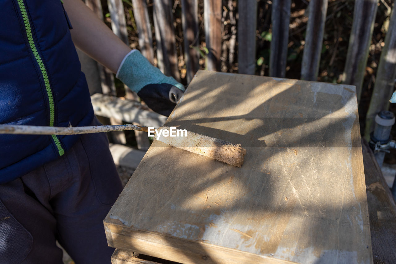 A child paints a wooden box with brushes in the garden