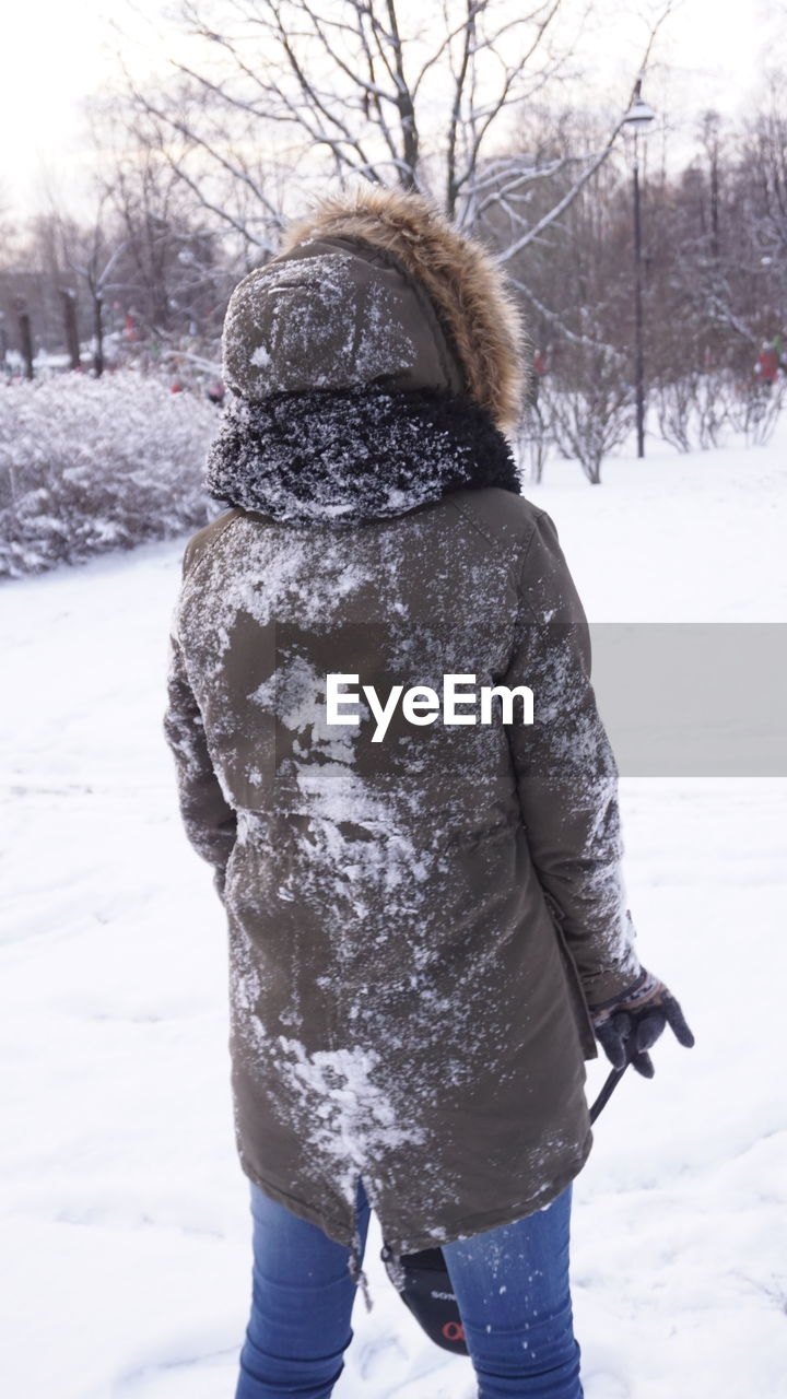 Rear view of a woman standing on snowed land