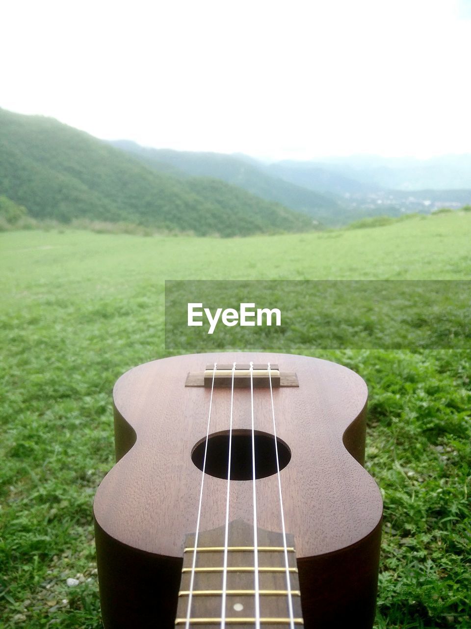 Close-up of guitar on field against sky