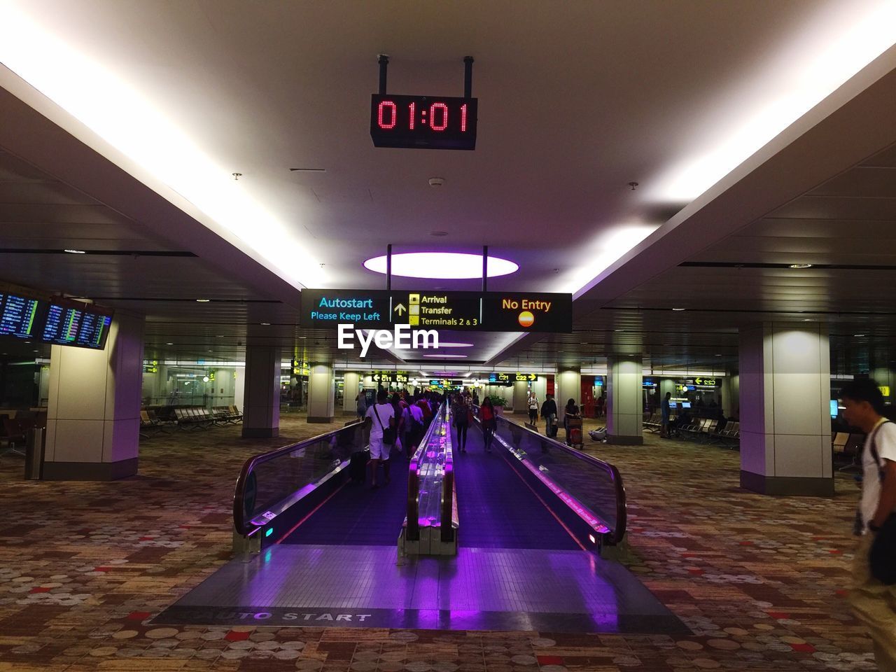 People walking on illuminated escalator at airport