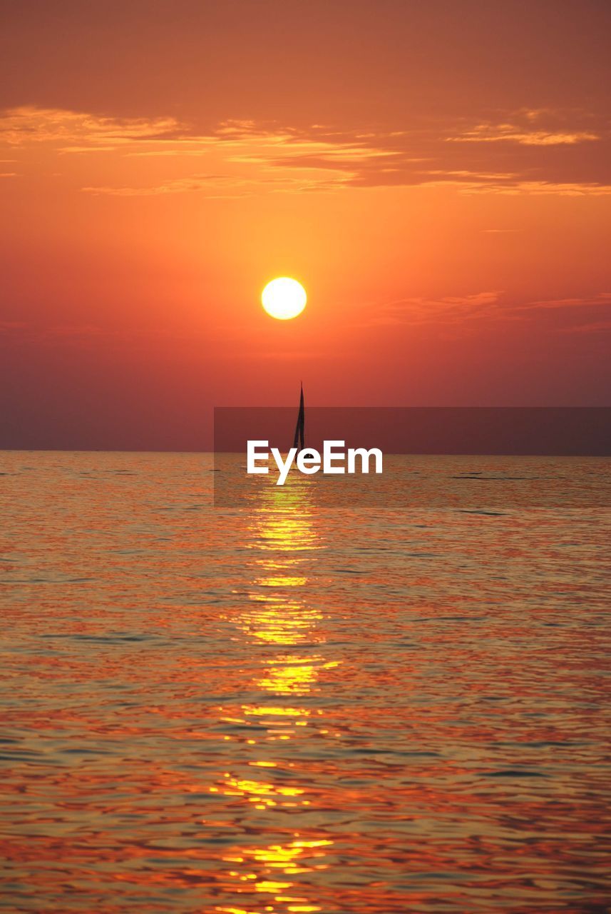 Sunset over lake michigan with a sailboat against an orange sky