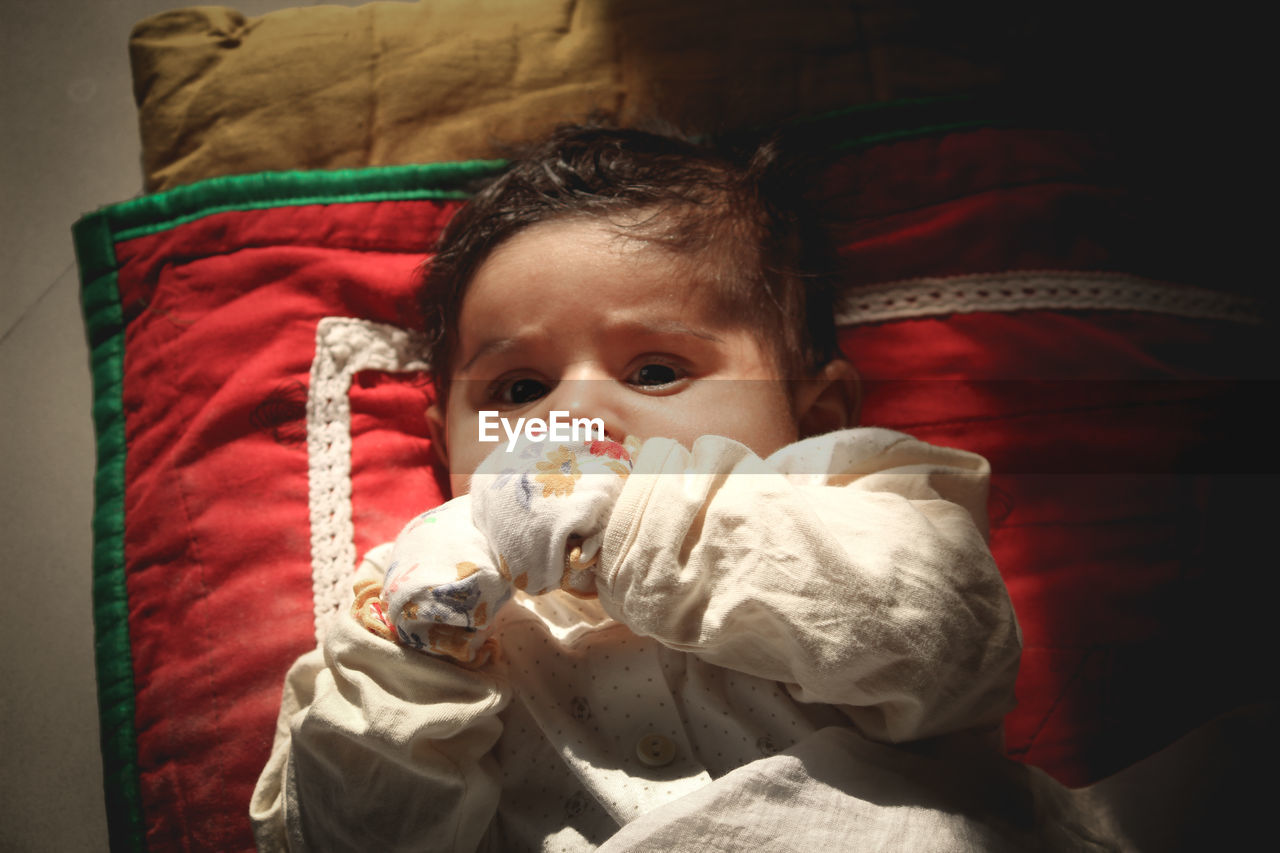 PORTRAIT OF CUTE BABY LYING ON BED AT HOME