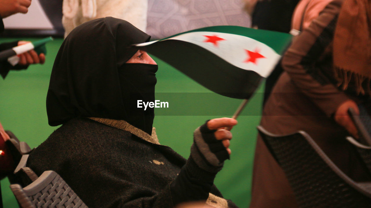 Woman holding syrian flag protesting outdoors