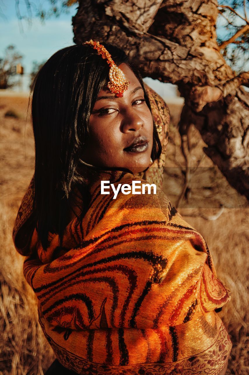 Close-up portrait of female model wearing traditional clothing by tree