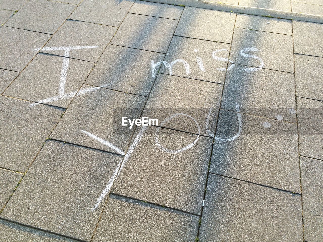 High angle view of i miss you text on footpath