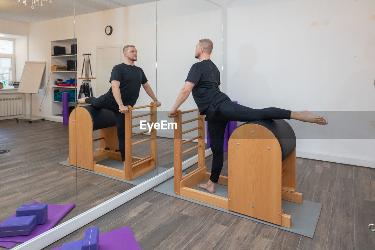 Male fitness pilates trainer shows exercises on special simulators. pilates stretch tables