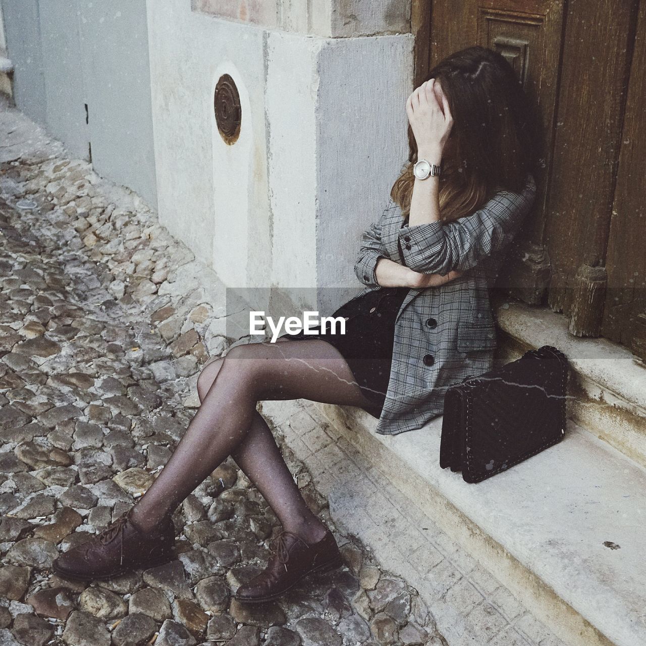 Woman sitting on doorway of house