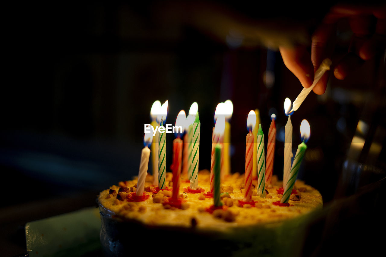 Hand lighting the candles on a cake.