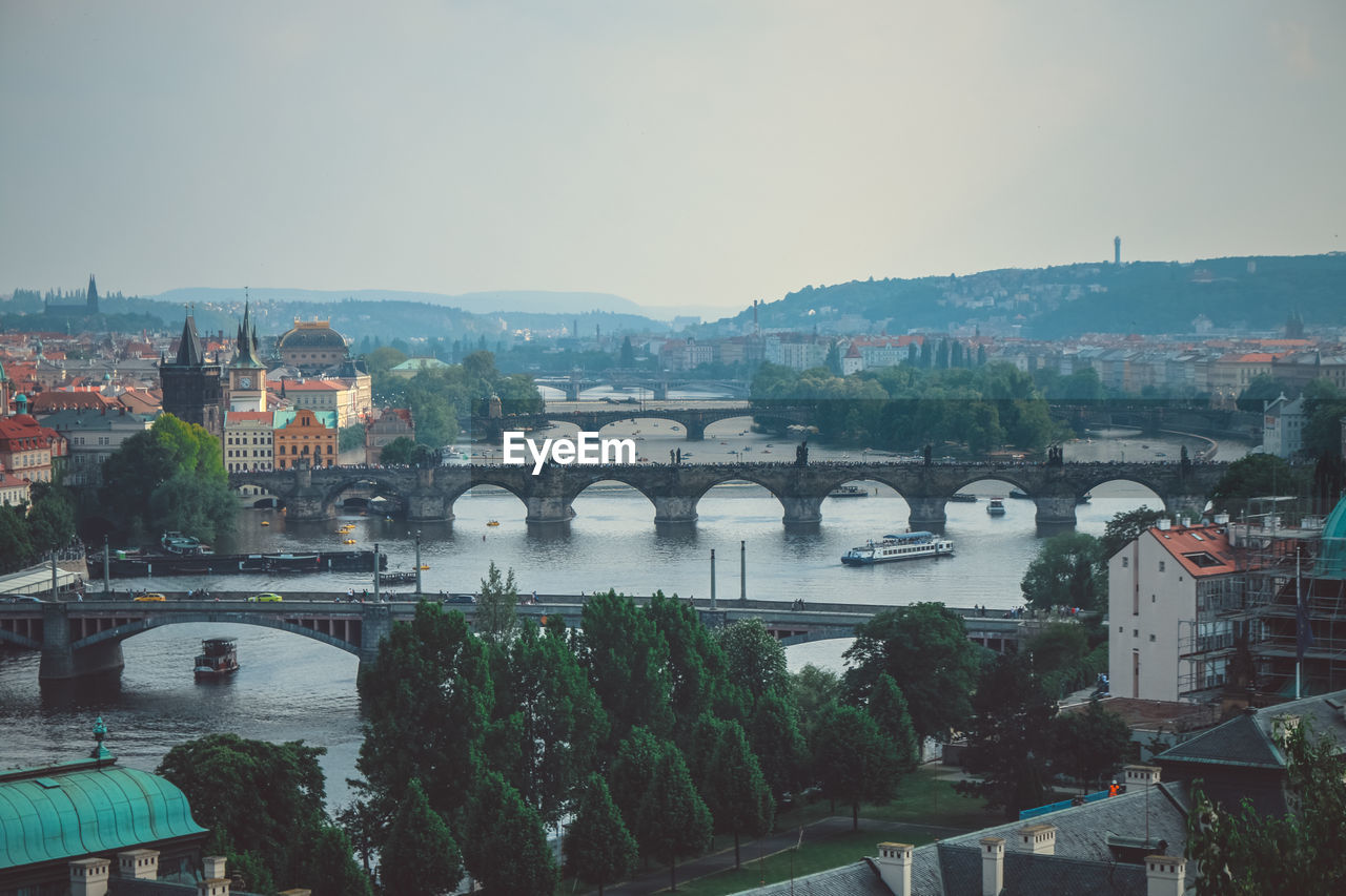 Bridge over river amidst buildings in city against sky