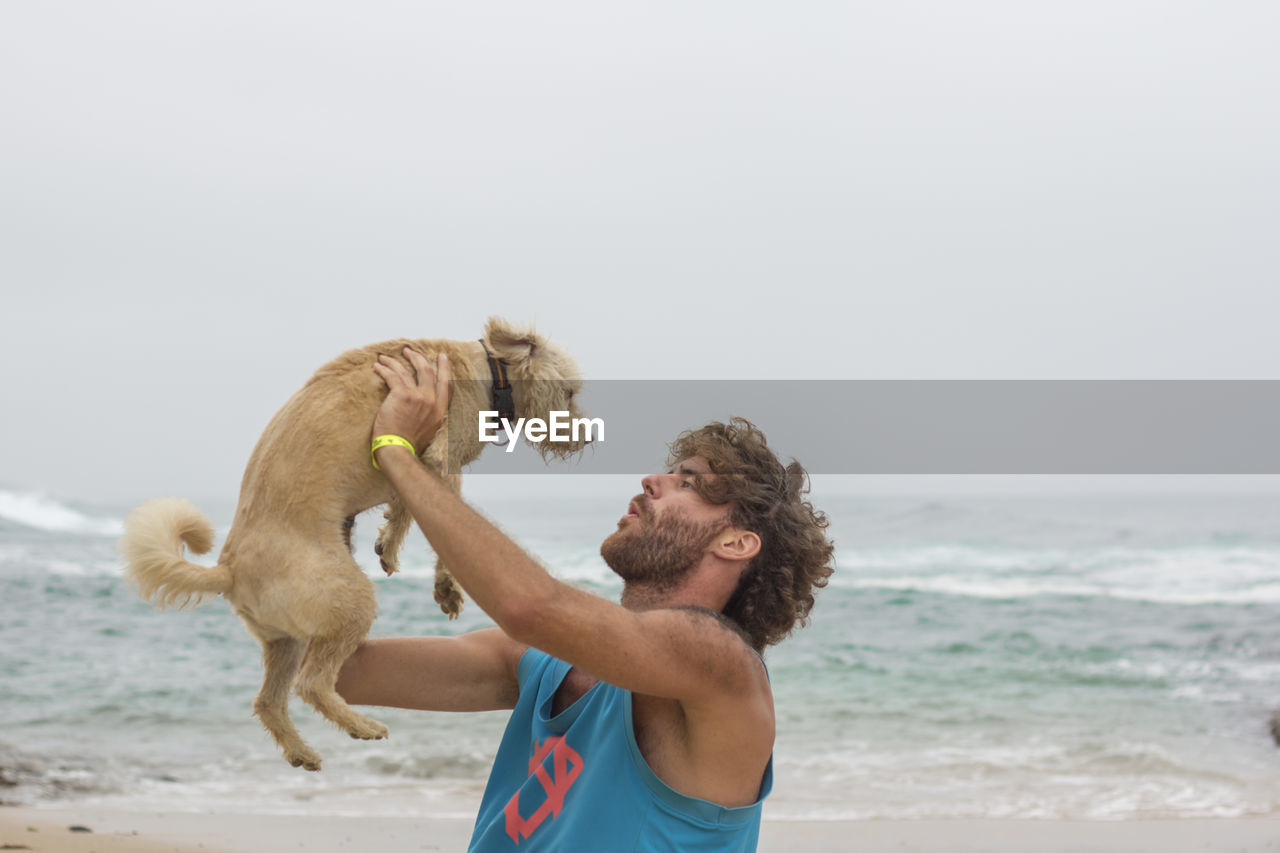 Man with dog playing on beach 