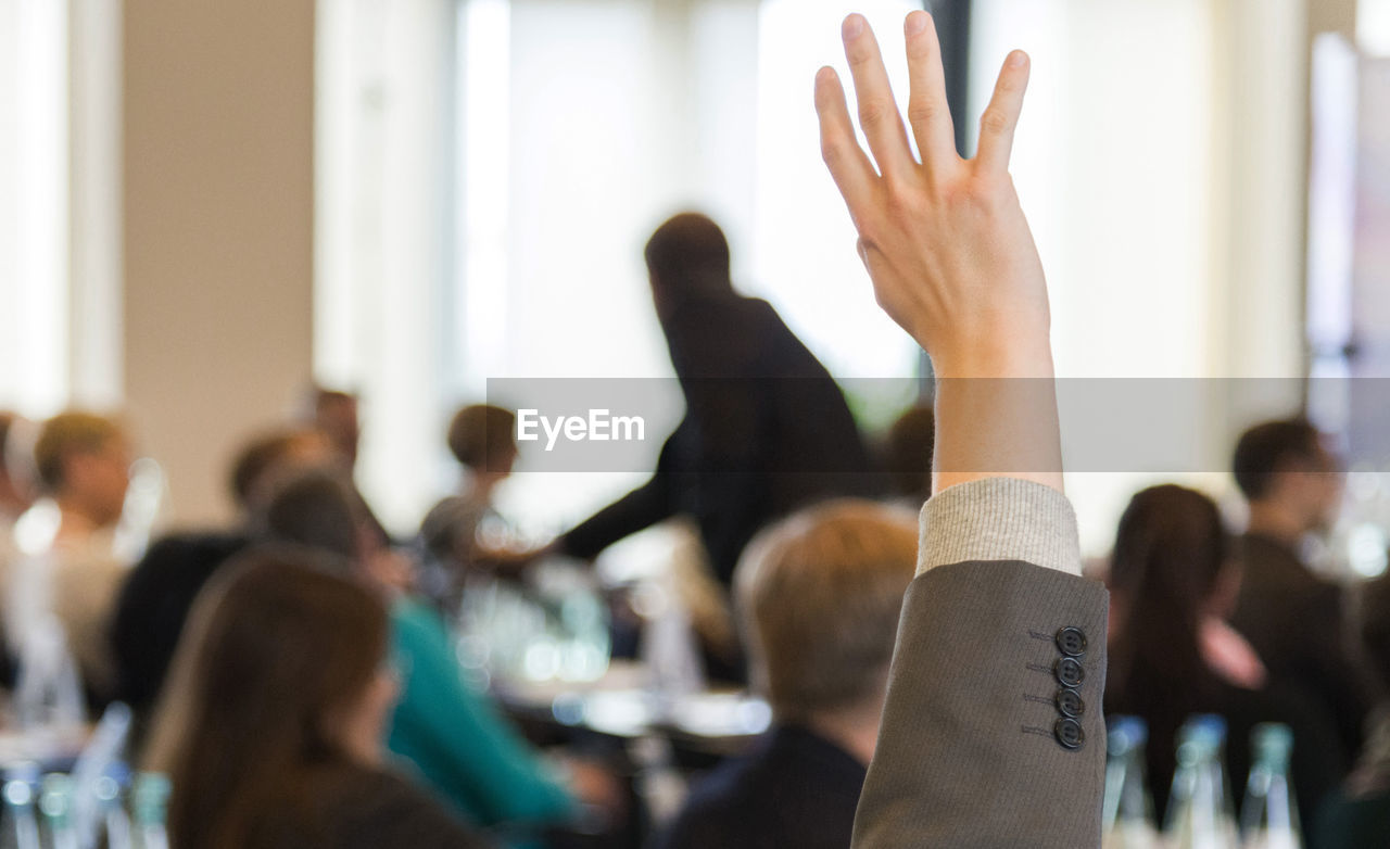 Close-up of businessman with hands raised at meeting
