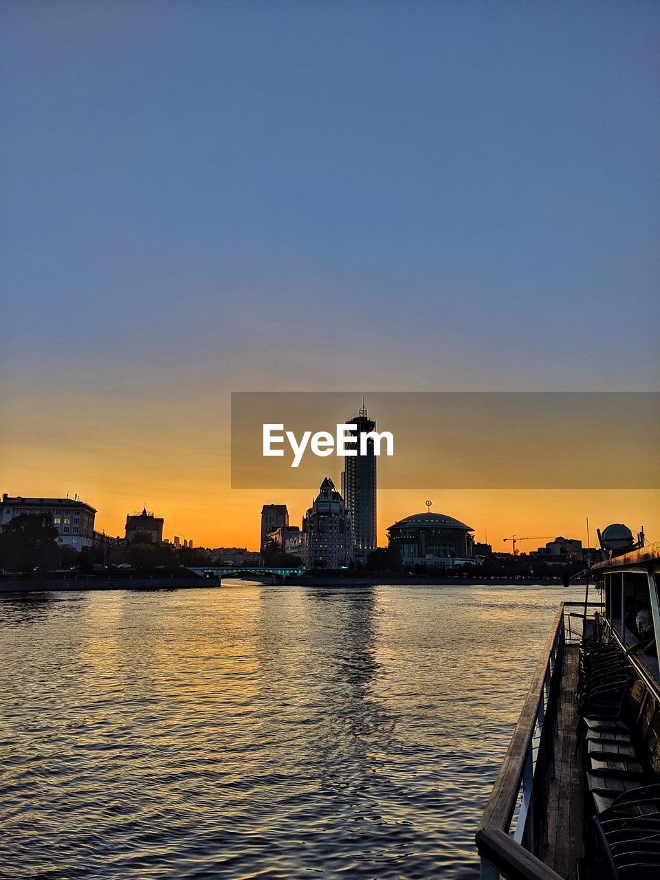 Sea by buildings against sky during sunset