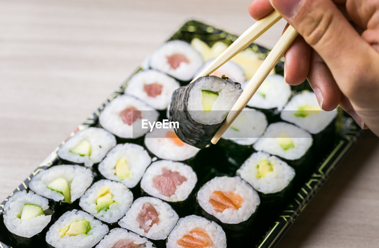 MIDSECTION OF PERSON HOLDING SUSHI IN TRAY