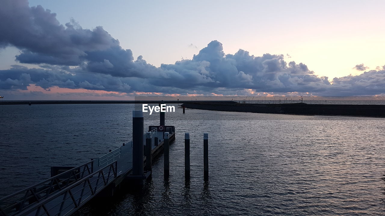 Pier over sea against sky at sunset