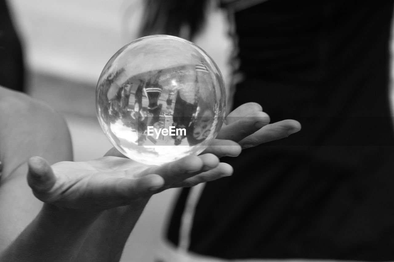 CLOSE-UP OF HANDS HOLDING CRYSTAL BALL