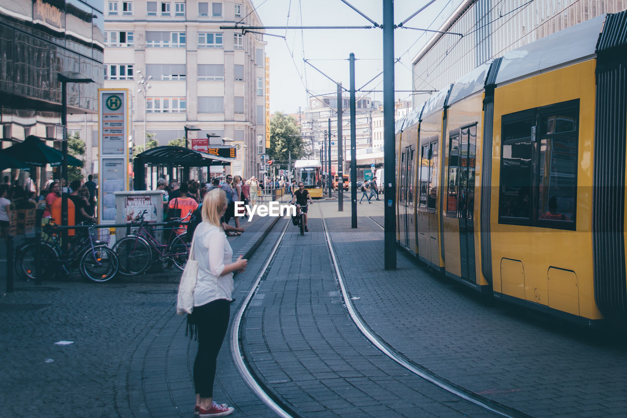 Side view of woman standing on street by tramway