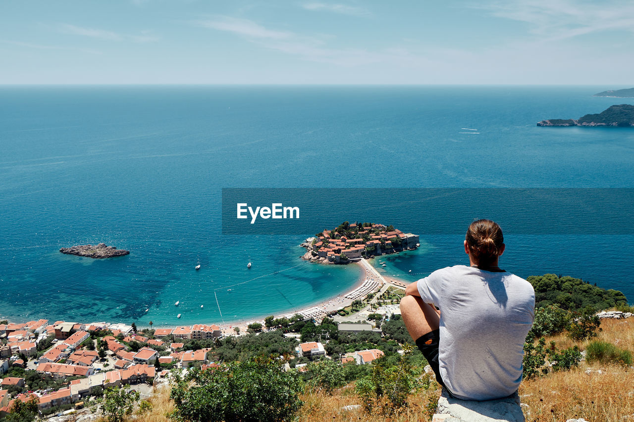 REAR VIEW OF MAN LOOKING AT SEA