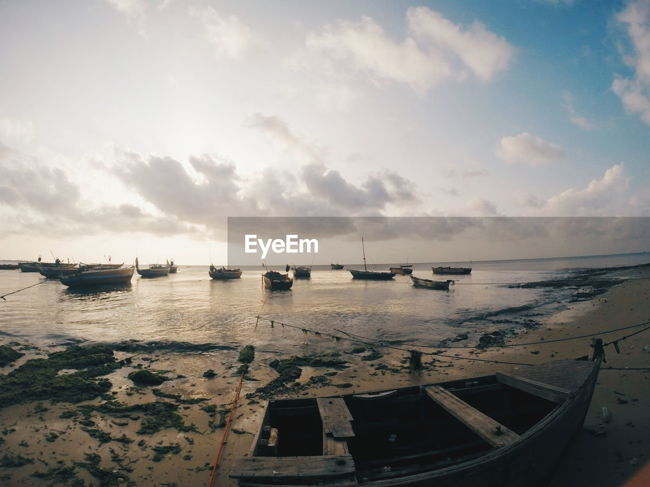 Fish-eye view of boats moored on seashore against sky