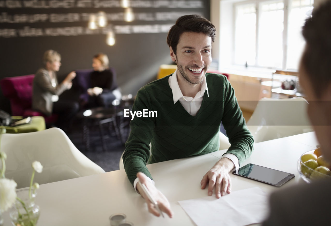 Happy businessman discussing with colleague at office desk