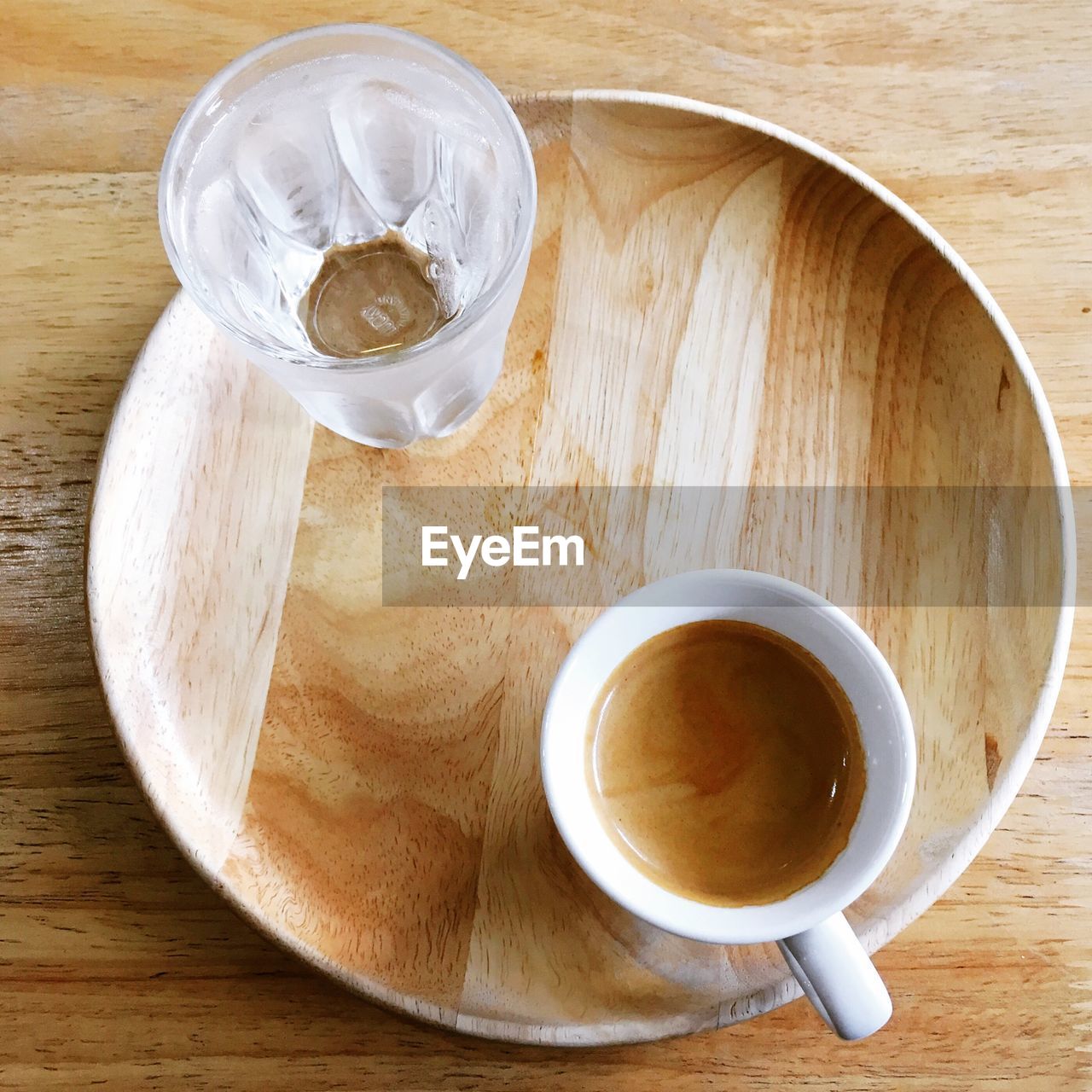 High angle view of coffee with drinking water in plate on wooden table