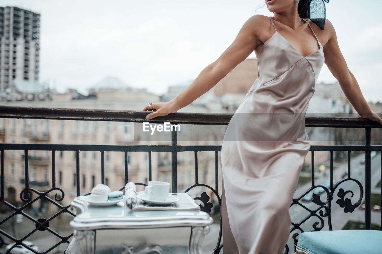 Midsection of woman standing by railing against balcony