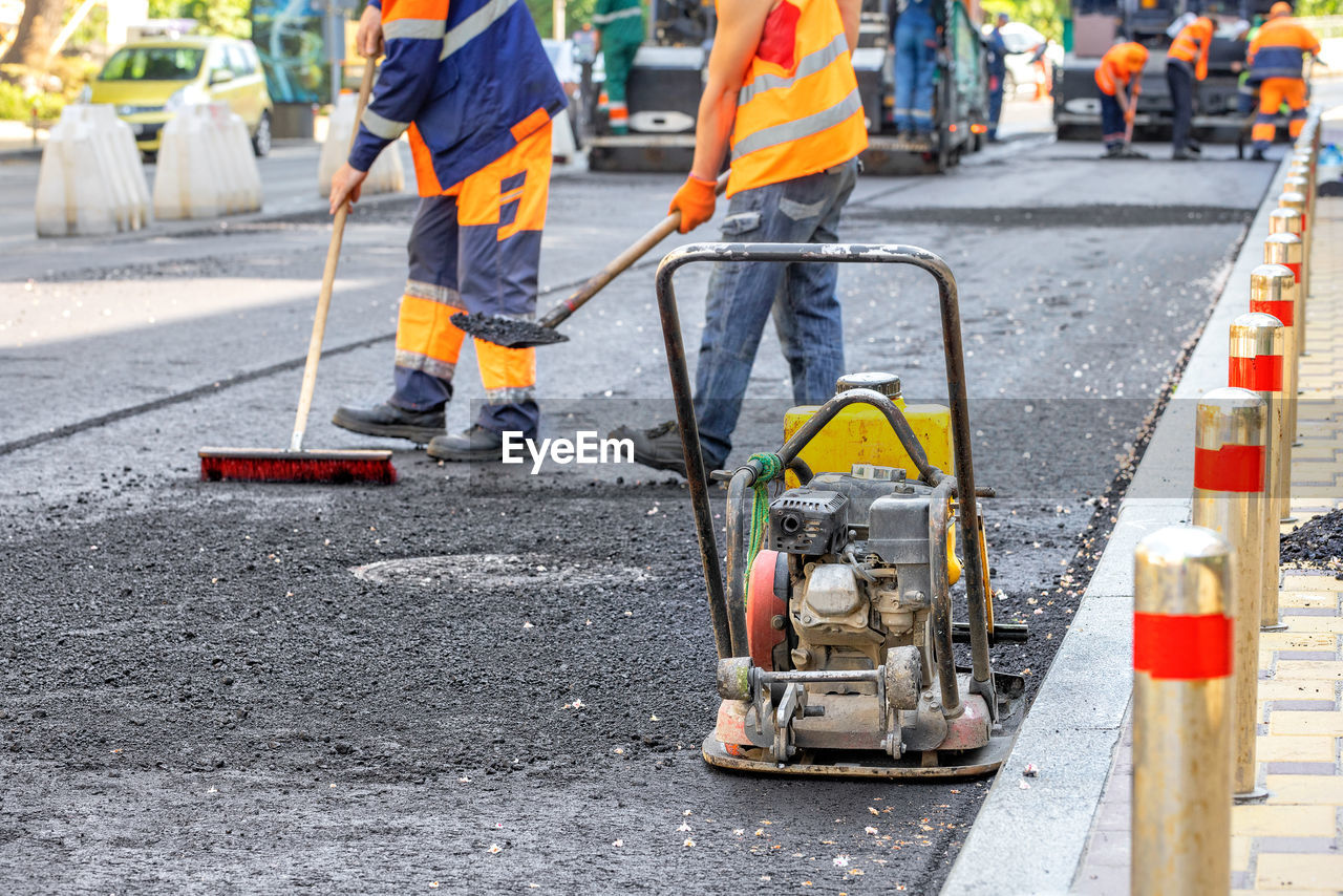 asphalt, road construction, road, occupation, reflective clothing, working, construction industry, transportation, industry, street, construction site, city, traffic cone, protection, cone, manual worker, construction worker, men, cooperation, group of people, sign, security, teamwork, road surface, day, protective workwear, adult, mode of transportation, coworker, equipment, clothing, outdoors, construction machinery, warning sign, headwear