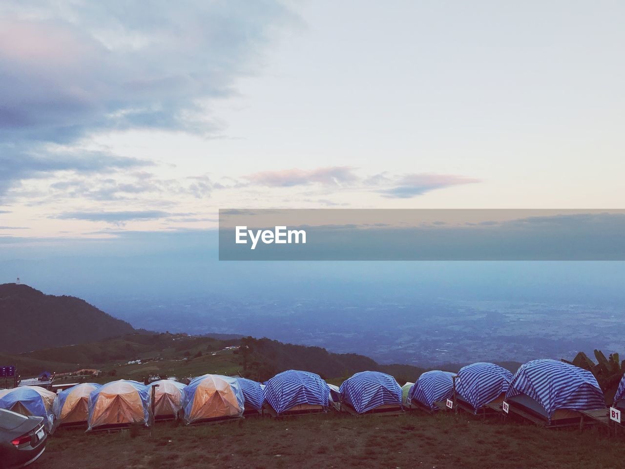 Tents on mountain against sky during sunset