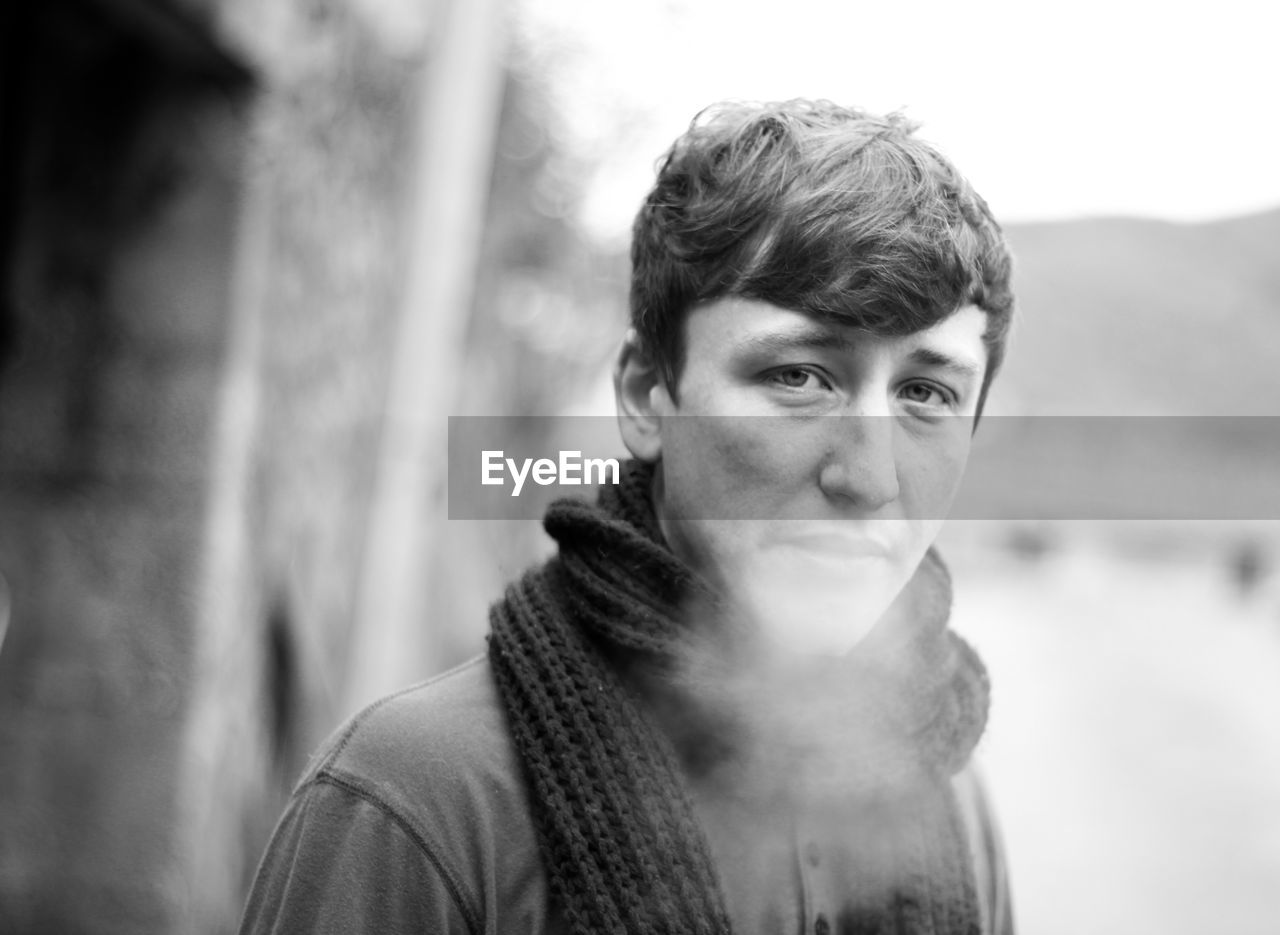 Close-up portrait of young man exhaling breath vapor