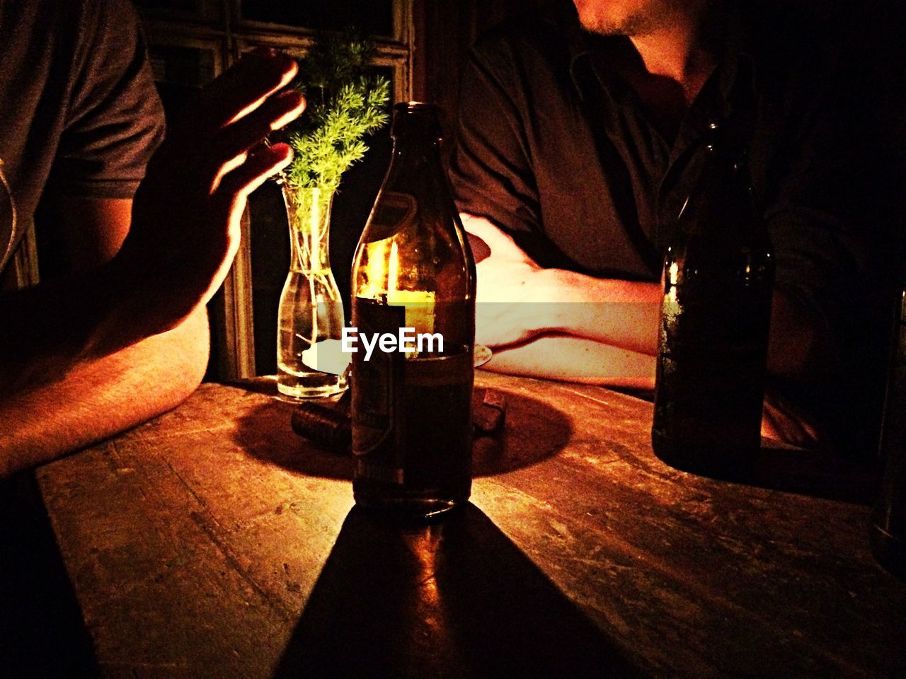 Mid section of two men with bottles sitting at table