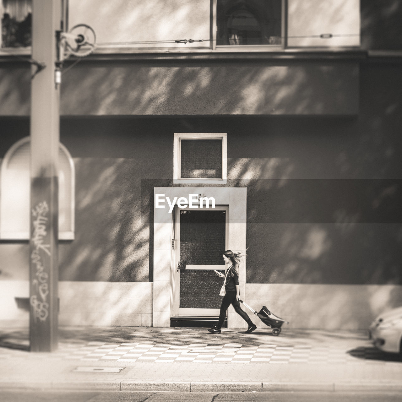 REAR VIEW OF MAN SITTING ON SIDEWALK BY BUILDING