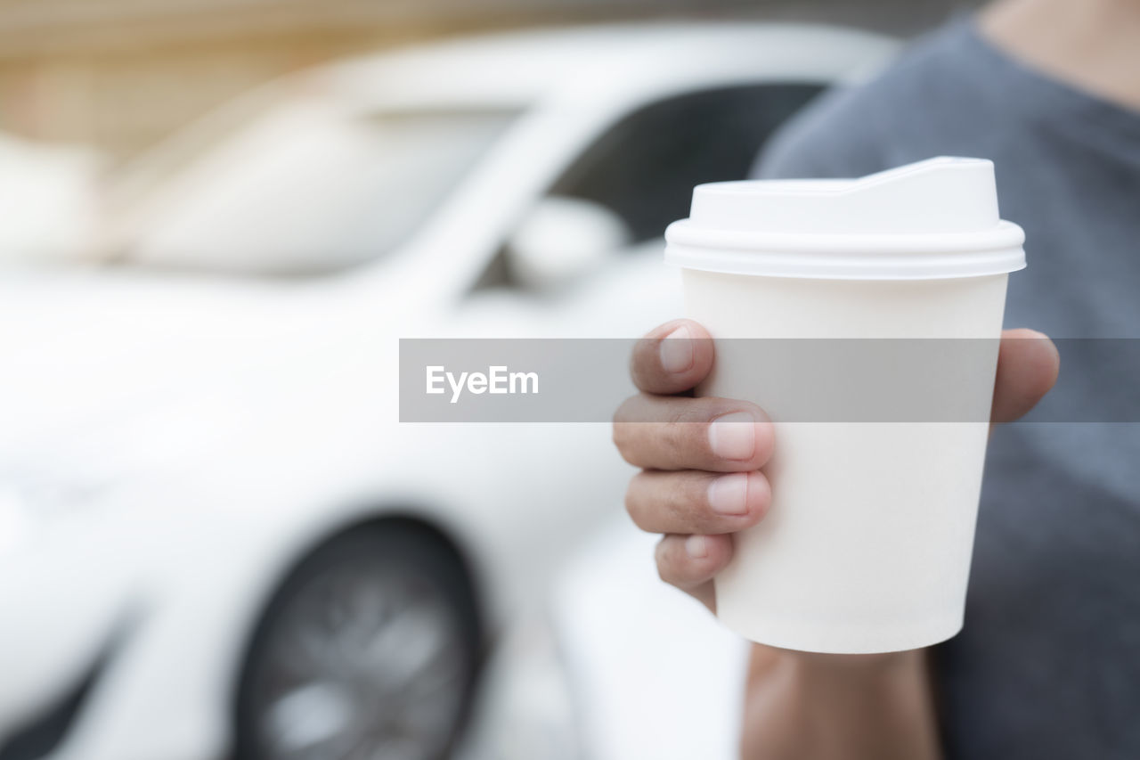 CLOSE-UP OF HAND HOLDING CUP OF COFFEE WITH SPOON